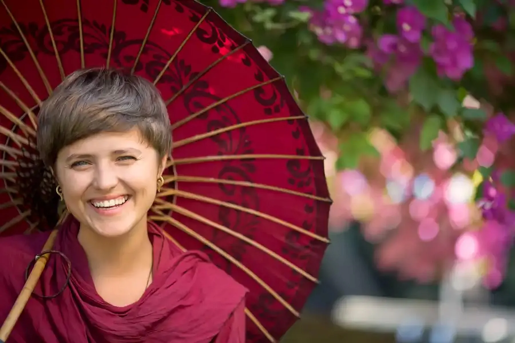 Une femme souriante tenant une ombrelle rouge