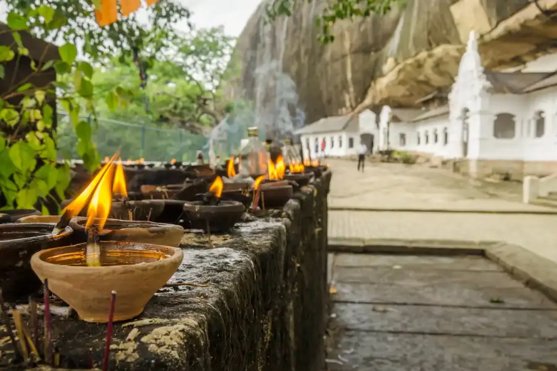 Des lampes à huile allumées près d’un temple troglodyte