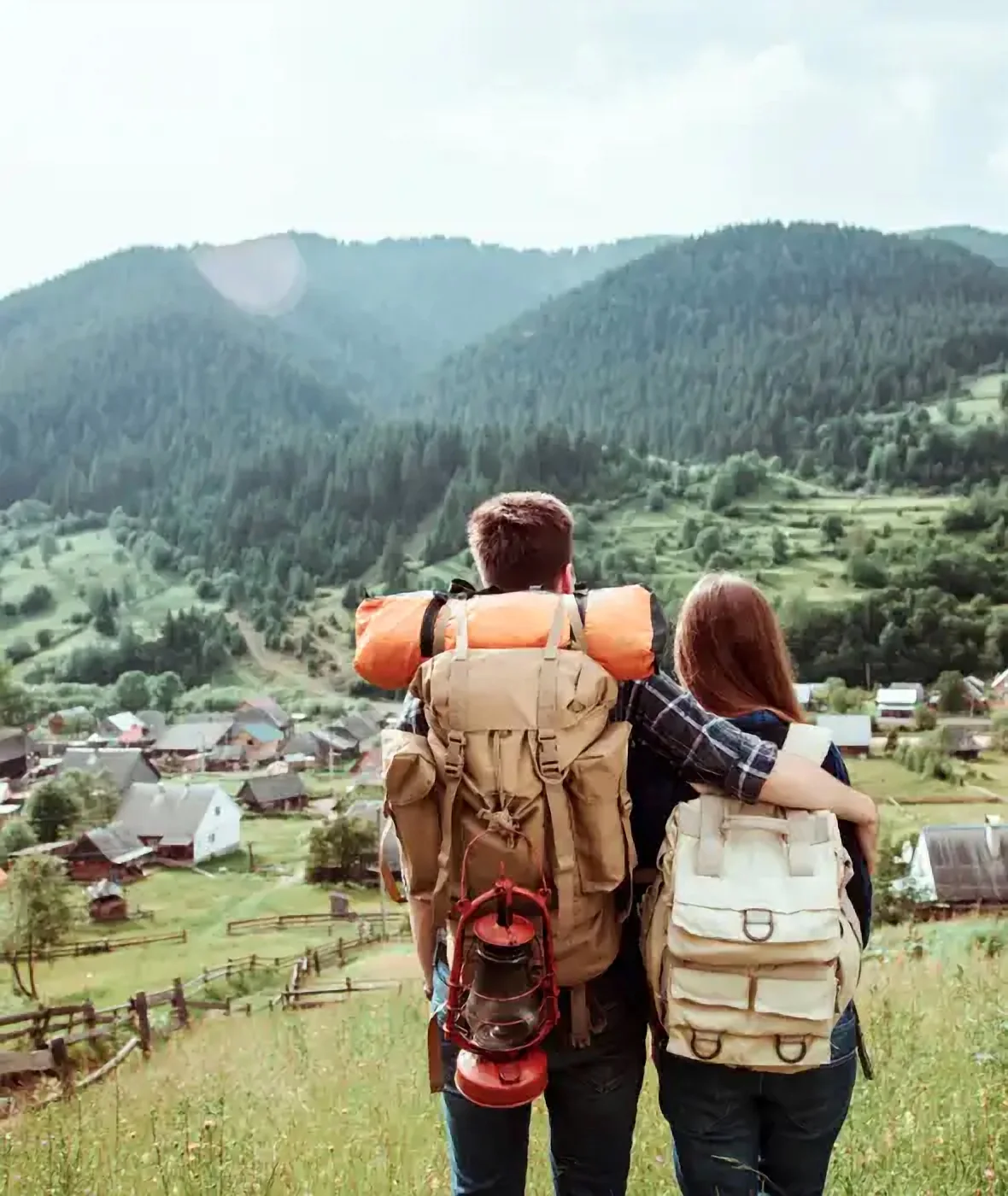 Two travellers with backpacks looking at a green valley