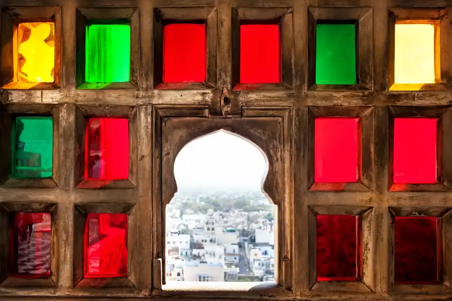 Une fenêtre aux vitraux colorés ouverte sur une ville