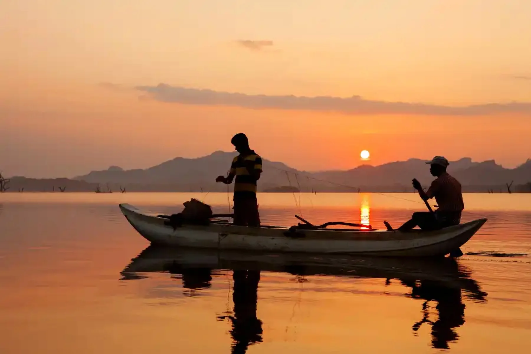 Des pêcheurs en barque au coucher du soleil